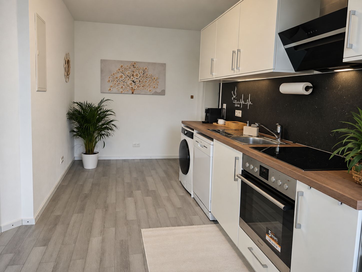 A modern kitchen with a wooden countertop, stainless steel appliances, and a potted plant.