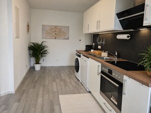 Eine moderne Küche mit einer Holzarbeitsplatte, Edelstahlgeräten und einem Blumentopf.