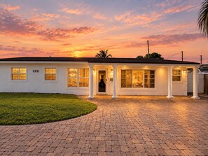 A single-story building with a number '120' on the side, a paved driveway, and a well-lit entrance. - Private Pool BBQ Outdoor Dining (Hollywood)