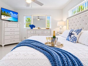 A bedroom with a bed, a dresser, a television, a ceiling fan, and a window with a view of palm trees. - Private Pool BBQ Outdoor Dining (Hollywood)
