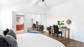 Un dormitorio con cama, escritorio y silla. Hay un ventilador de techo y un espejo en la pared.
