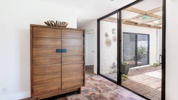A modern interior with a wooden cabinet, a sliding glass door leading to an outdoor patio, and a tiled floor.