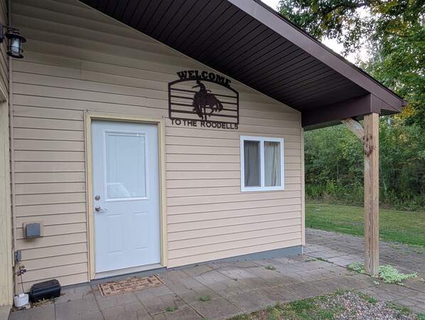 A building with a 'WELCOME TO THE ROODELLS' sign, a white door, and a small window.
