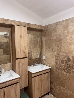 Ein Badezimmer mit zwei Waschbecken, Holzschränken und einem großen Spiegel.