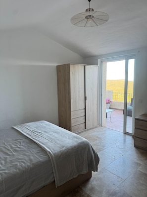 Ein Schlafzimmer mit einem Bett, einem Kleiderschrank und einer Glastür zum Balkon.