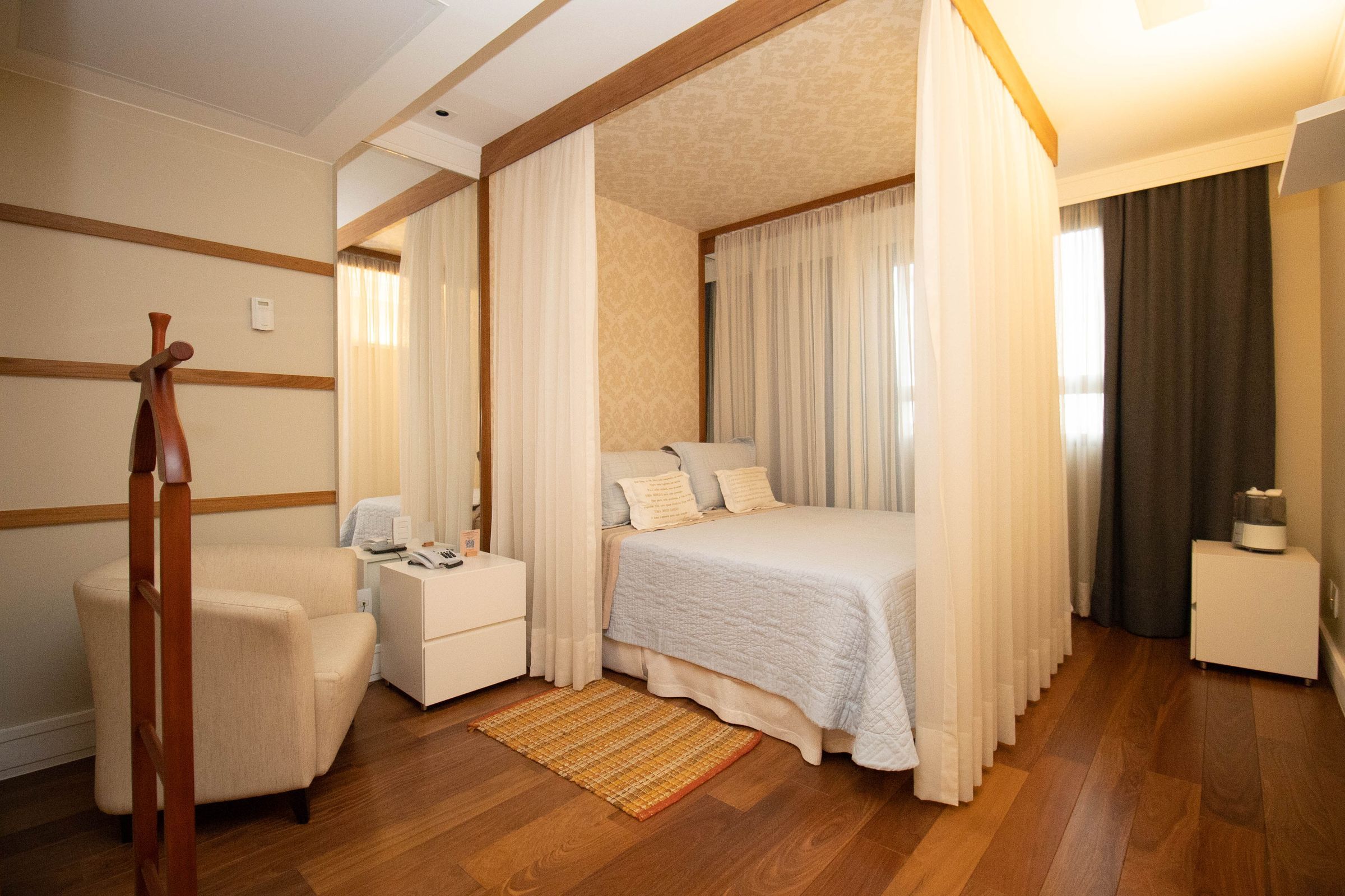 Una camera d'albergo con un letto, una sedia, un comodino e un piccolo armadio.
