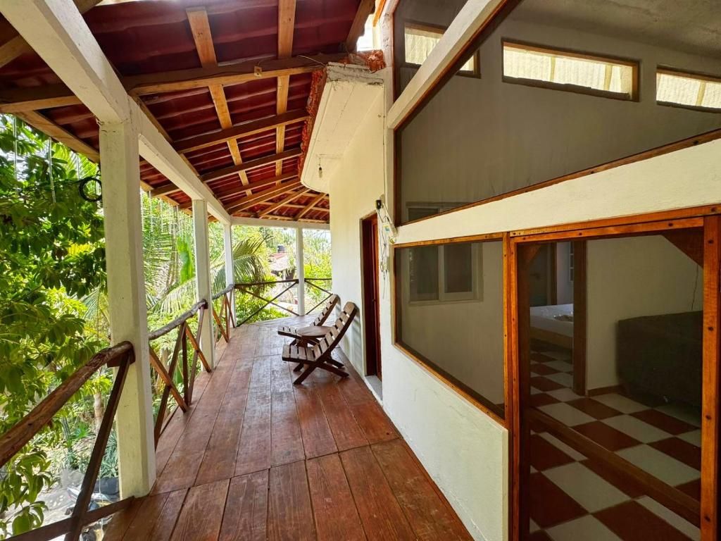 A covered outdoor area with a wooden deck, a bench, and a view of greenery.