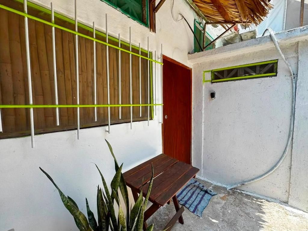 A small outdoor area with a wooden bench, a door, and a wall with a barred window.