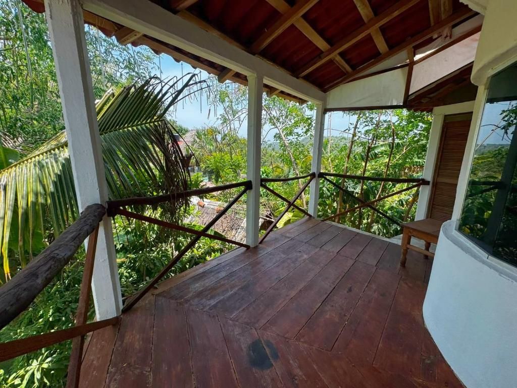Une terrasse en bois offrant une vue sur une végétation luxuriante, un banc en bois et un mur blanc.