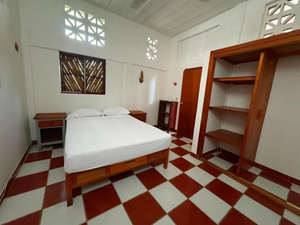 Una habitación con cama, armario, mesita de noche y ventana con diseño de celosía.