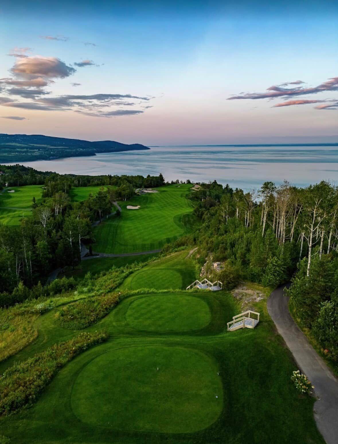 A golf course with a view of the ocean and a clear sky.