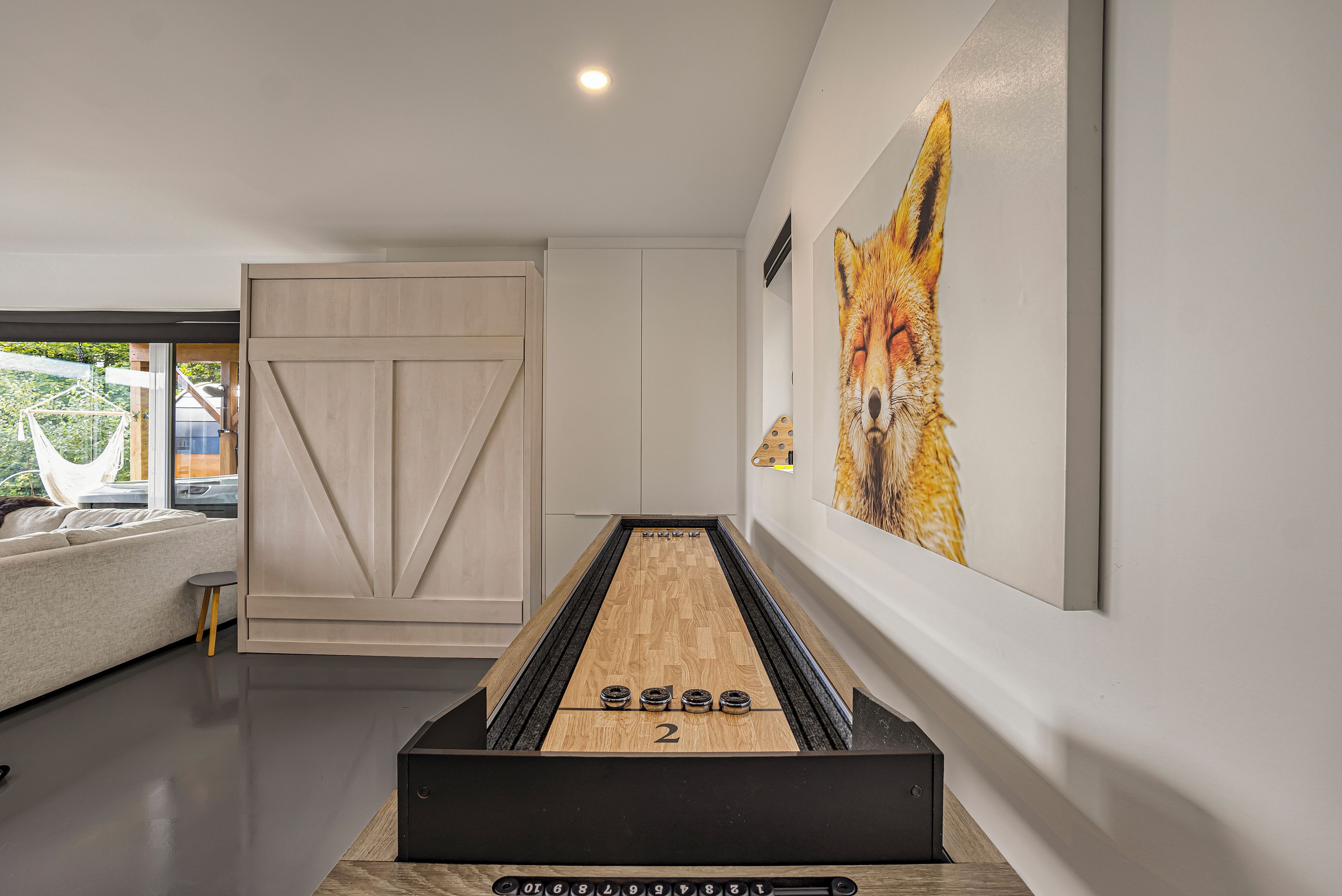 A modern interior with a billiards table, a sofa, and a large painting of a fox.