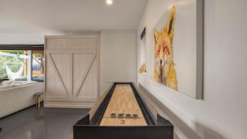 A modern interior with a billiards table, a sofa, and a large painting of a fox.