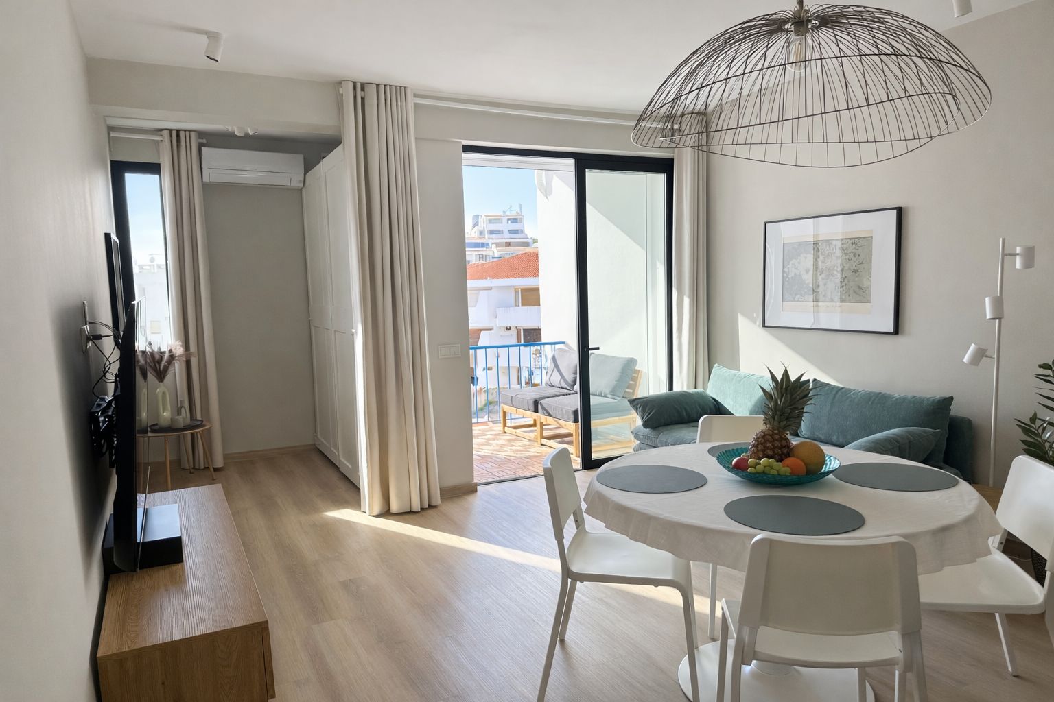 A modern living room with a dining area, a large window, and a view of the outside.