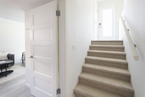 A staircase leading to an upper floor with a carpeted finish. - The Hugo Suite: Modern & Boutique (Winnipeg)