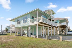 Une maison à deux étages située en bord de mer, dotée d’un balcon, d’une véranda et d’un garage apparent.
