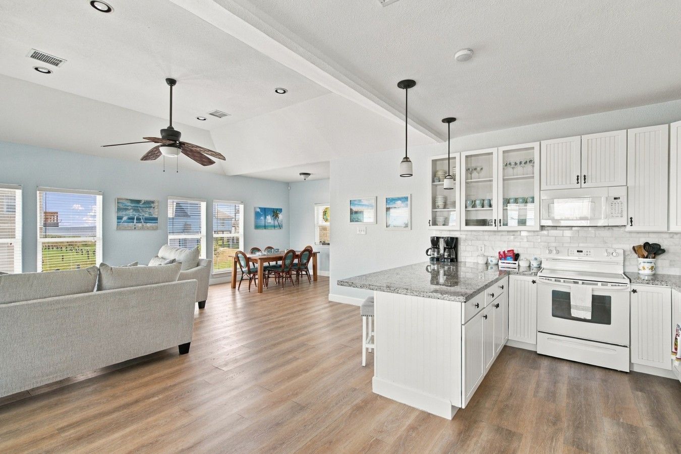 A modern kitchen with white cabinetry, a central island, and a dining area with a table and chairs.