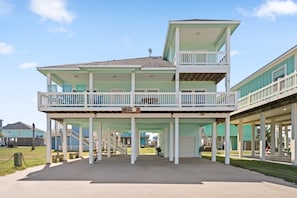 A multi-story building with a balcony, a covered walkway, and a sign indicating a beach location.