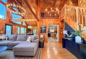 A spacious living area with a sectional sofa, a dining area, and a kitchen. - Sunset Mtn Views + Sauna, Whirlpool Tub, Game Room (Bryson City)