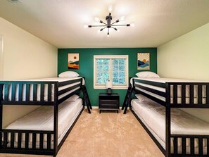 A room with bunk beds, a ceiling fan, a window with blinds, and artwork on the walls. - Sunset Mtn Views + Sauna, Whirlpool Tub, Game Room (Bryson City)
