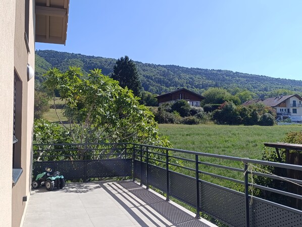 Un balcón con vistas a un campo verde y casas al fondo.