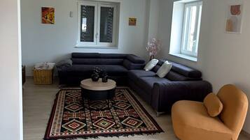 Un vaste espace de vie comprenant un canapé d’angle, une table basse ronde et un tapis à motifs.