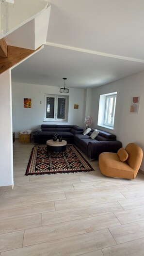 Amplia sala de estar con un sofá modular, una mesa de centro redonda y un tapete estampado.