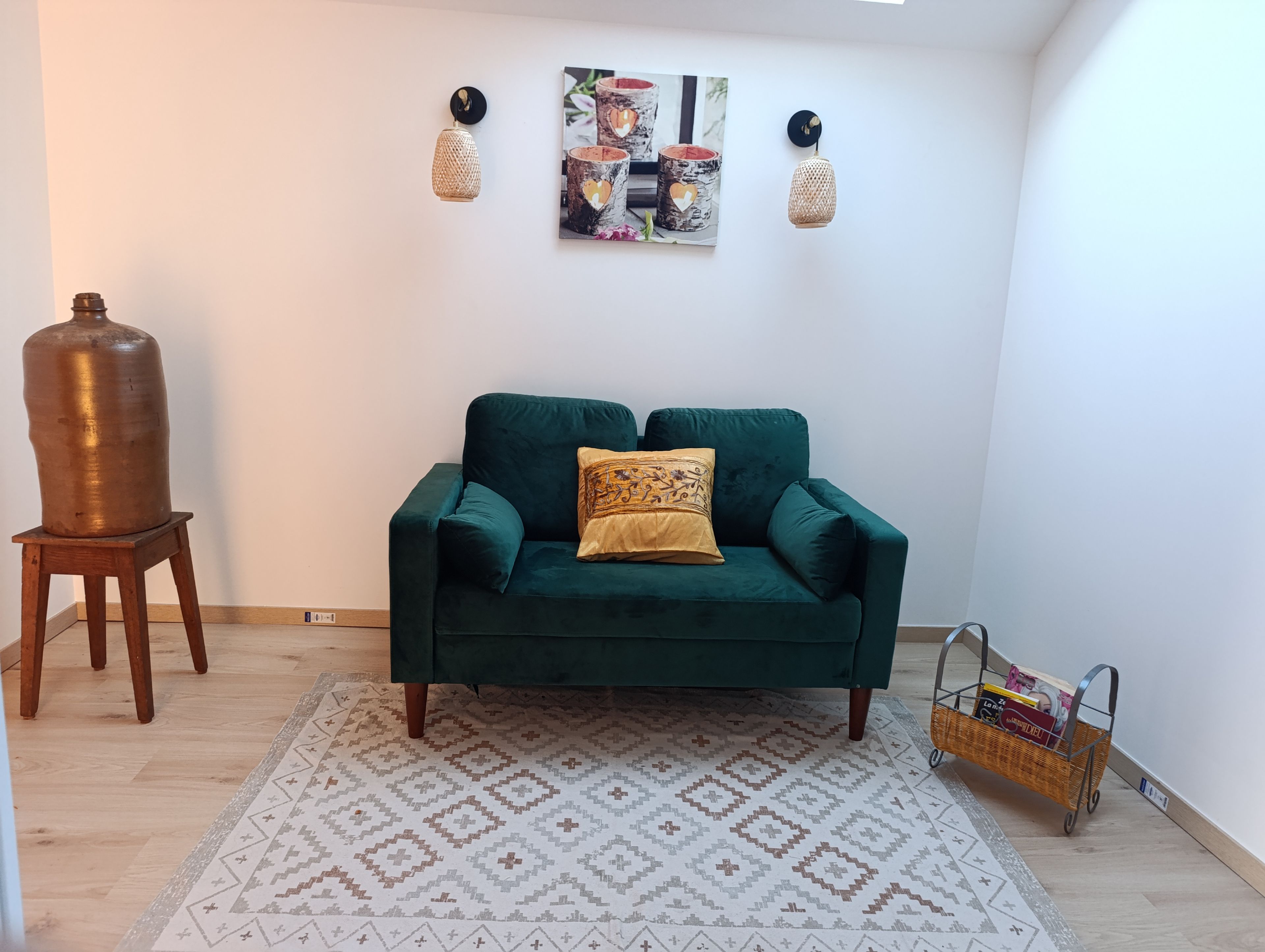A living room with a green sofa, patterned rug, and wall-mounted lights.