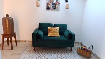 A living room with a green sofa, patterned rug, and wall-mounted lights.