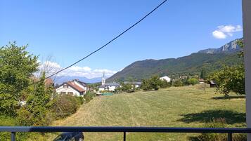 A rural landscape with a church, houses, and mountains in the background.