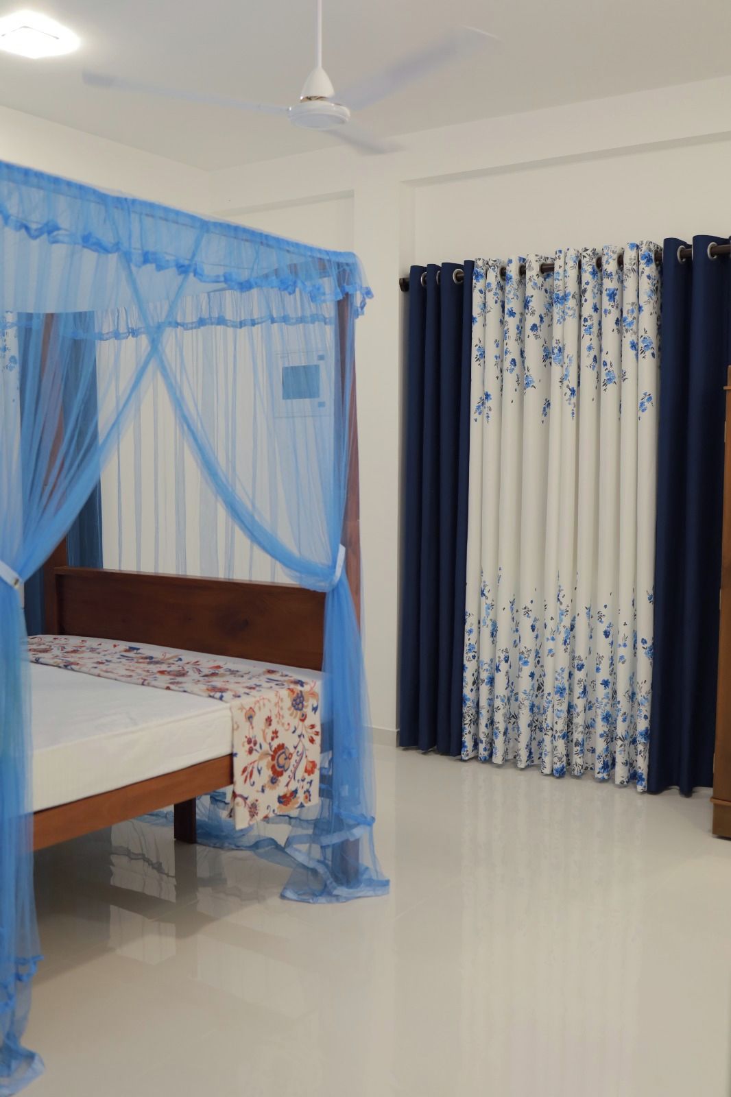 A bedroom with a bed, a ceiling fan, and curtains.