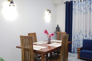 Un coin repas avec une table en bois, des chaises et un vase rempli de fleurs.