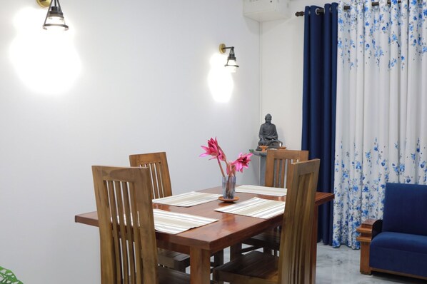 A dining area with a wooden table, chairs, and a vase with flowers.