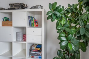 A bookshelf with books, a typewriter, and a plant.