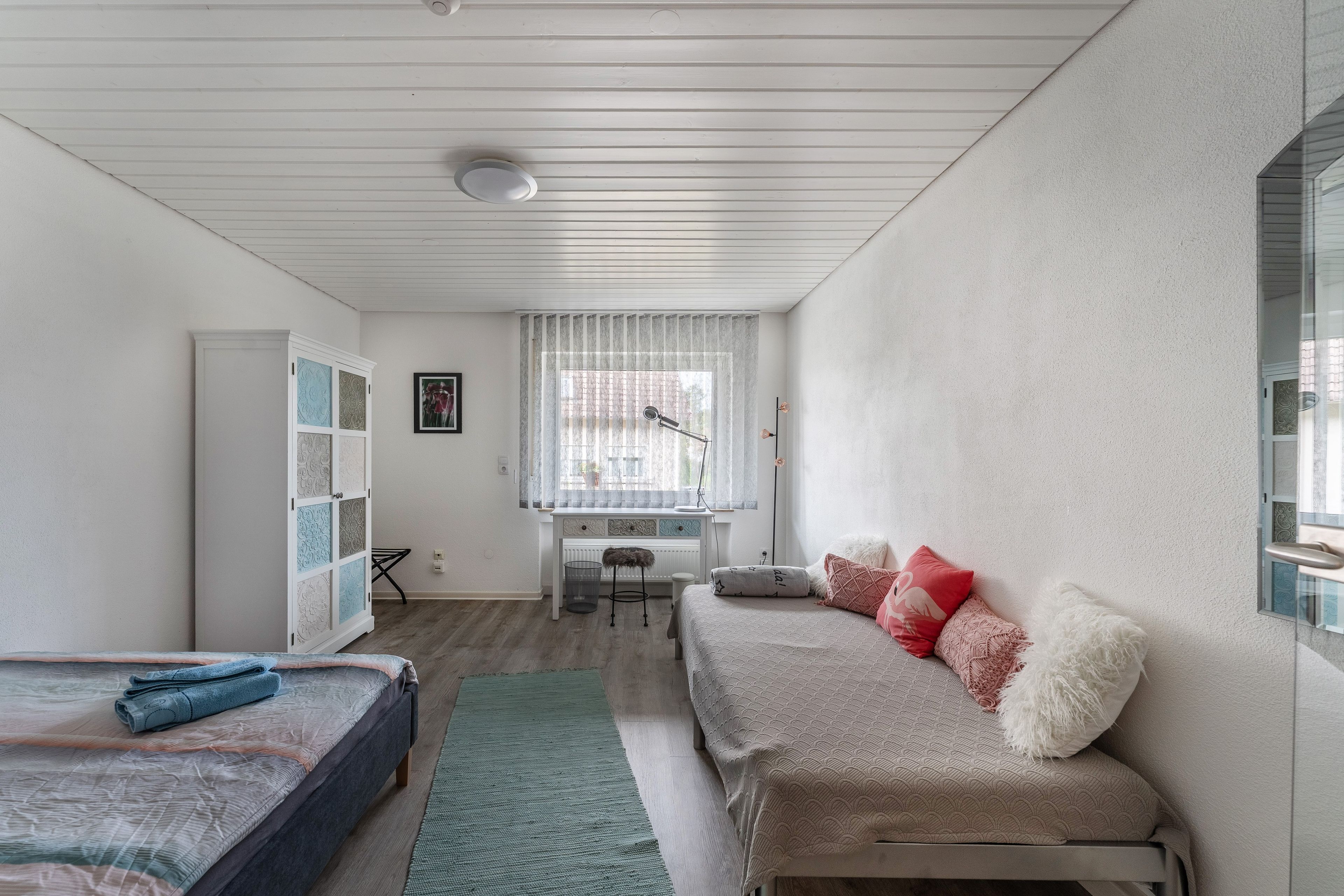 Un dormitorio con cama, escritorio y ventana.