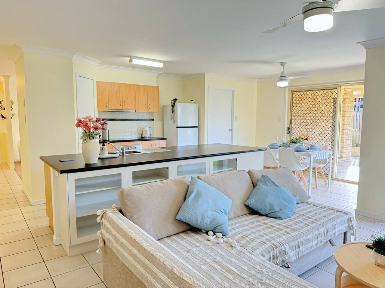 A modern kitchen with a central island, a dining area with a table and chairs, and a living area with a sofa.