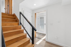 Eine Holztreppe mit schwarzer Handlauf, die zu einer weißen Tür führt.