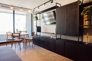 A modern kitchen with a large flat-screen TV, wooden chairs, and a dining table. - Prime 1BR Flat in Las Condes Parking (Las Condes)