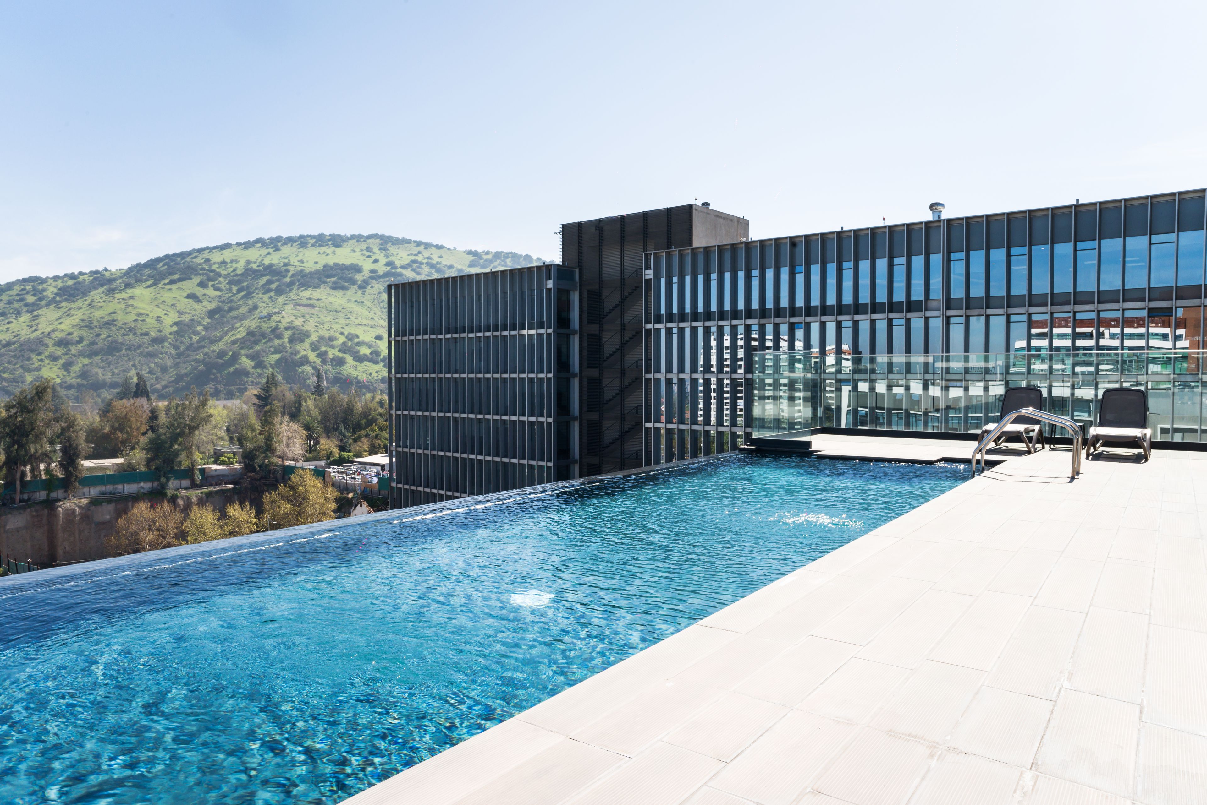 A modern building with a glass facade overlooking a swimming pool.