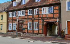 A traditional half-timbered building with multiple windows, a wooden door, and a stone foundation. - Cozy apartment in Röbel with lake view (Röbel)