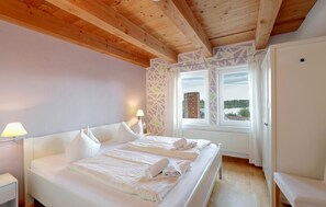 A hotel room with a wooden ceiling, a large bed with white linens, a window with a view of a brick building, and a white door. - Pet friendly apartment in Röbel with lake view (Röbel)