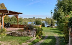 A covered outdoor seating area with a grill, a stone wall, and a view of a lake. - Pet friendly apartment in Röbel with lake view (Röbel)