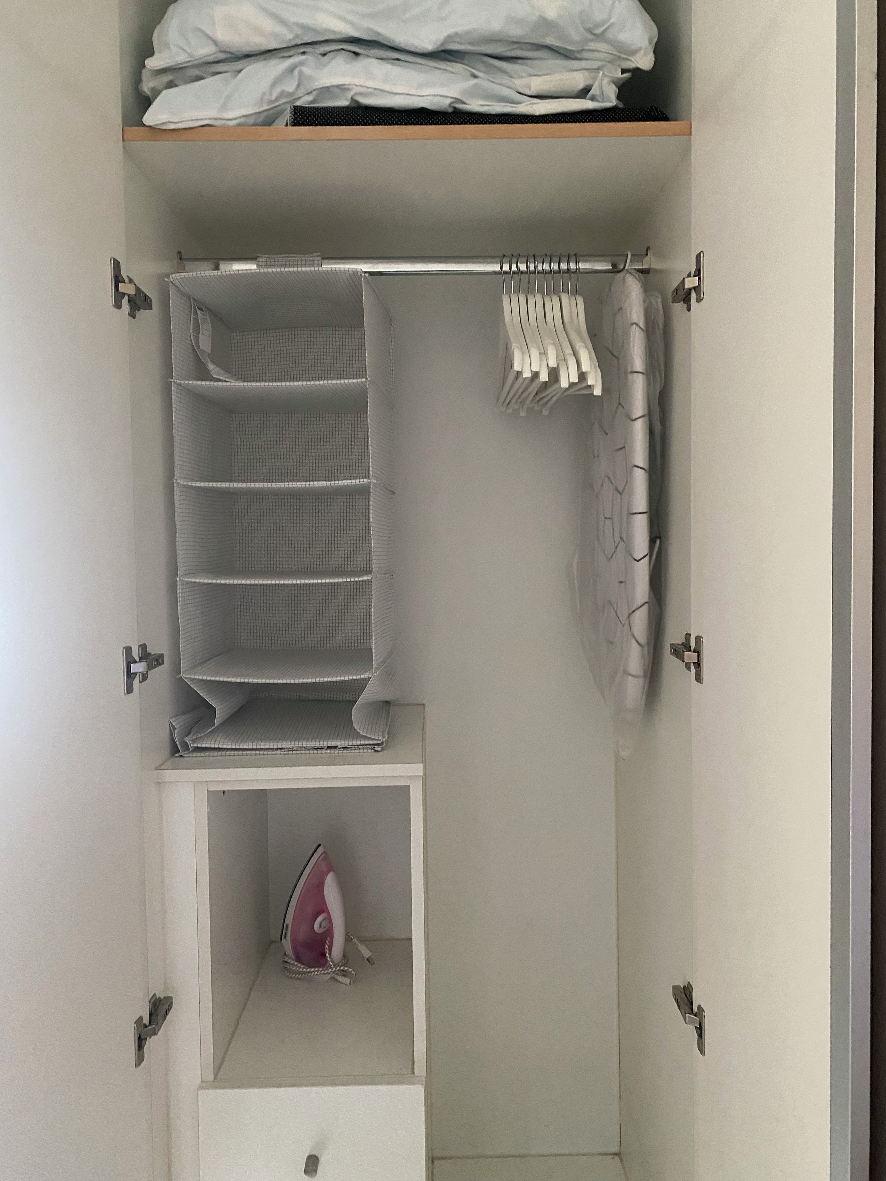 A closet with shelves, hanging space, and a storage box.
