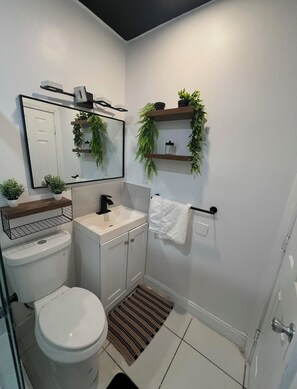 Ein modernes Badezimmer mit Toilette, Waschbecken, Spiegel und Handtuchhalter.