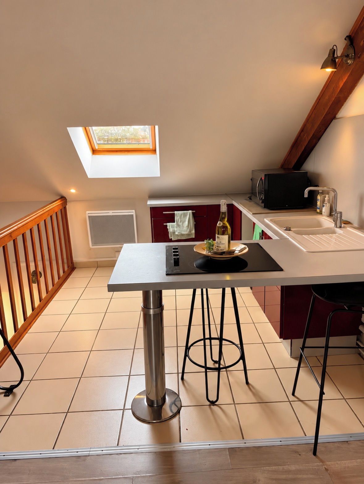 Une cuisine compacte avec une table à manger, un four à micro-ondes encastré et une petite fenêtre.