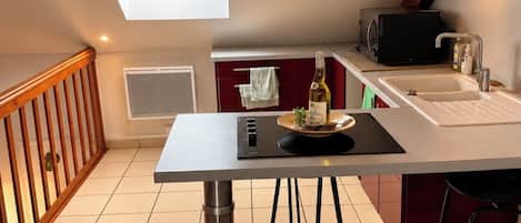 Ett kompakt kök med ett matbord, en inbyggd mikrovågsugn och ett litet fönster.