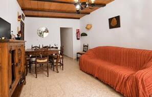 A dining area with a wooden table and chairs, a sofa, and a ceiling with wooden beams. - Amazing home in Iznajar with private swimming pool, can be inside or outside (Iznajar)