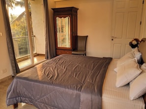 A bedroom with a large bed, a chair, a wardrobe, and a door. - Luxurious 3-bedroom apartment villa with private pool in tranquil Candolim (Candolim)
