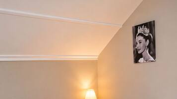 Un dormitorio con cama, mesita de noche, lámpara y un cuadro en la pared.