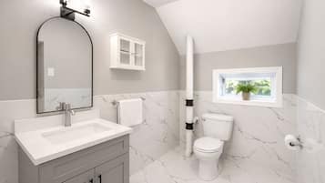 A bathroom with a white sink, a mirror, a toilet, and a window with a plant.